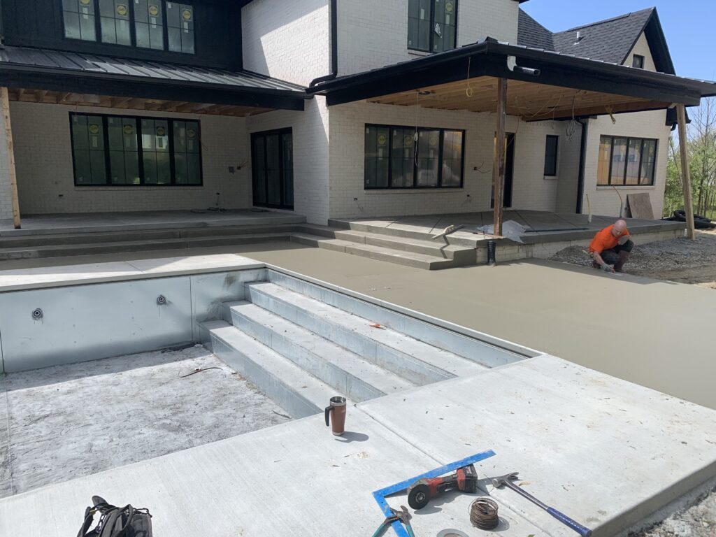 Custom residential patio installation with stamped concrete for the patio, steps, and walk way around the installed pool,.